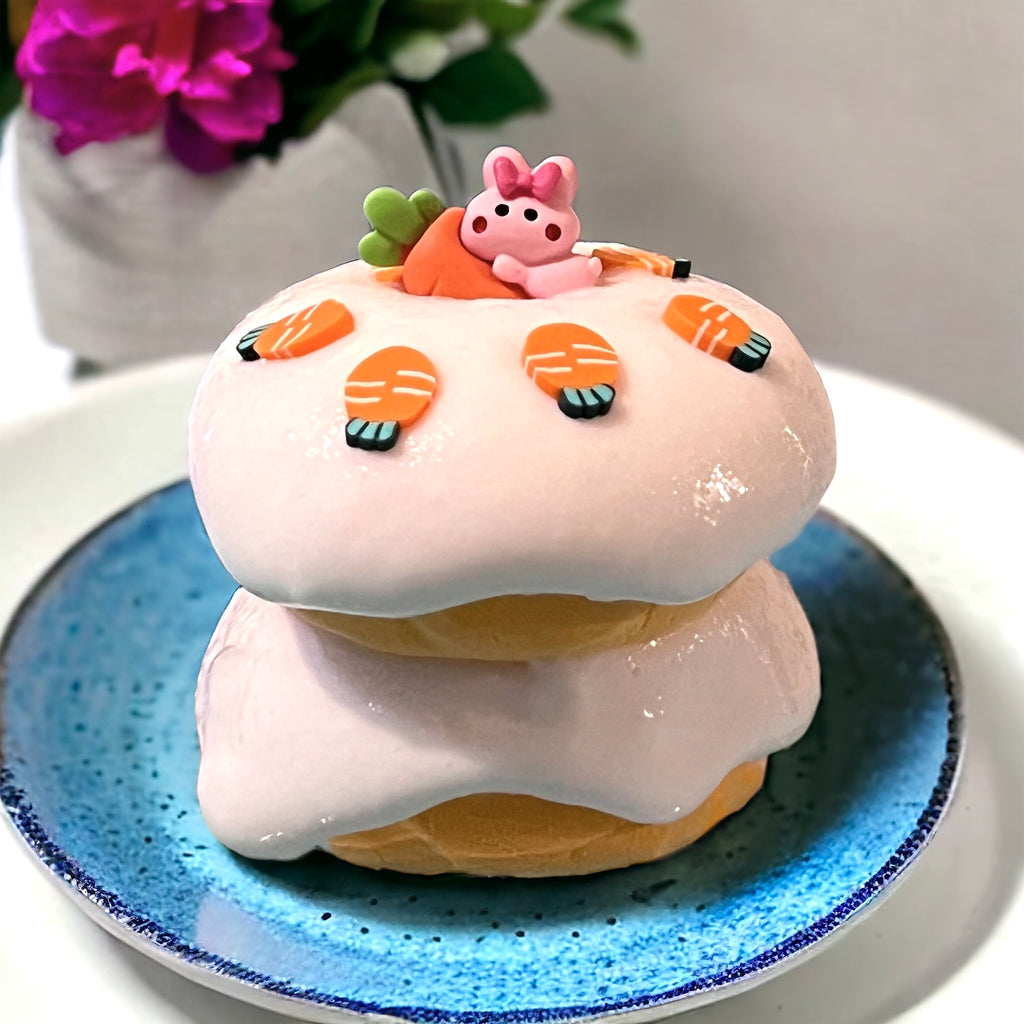 Two orange clay cakes stacked with glossy "icing" slime betwee then, and ontop, with carrot clay slices and cute bunny charm decorating the "cake"